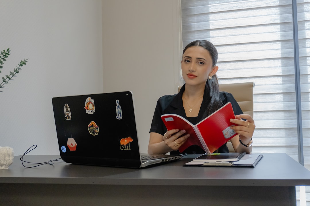 Woman reading a book at an office desk.