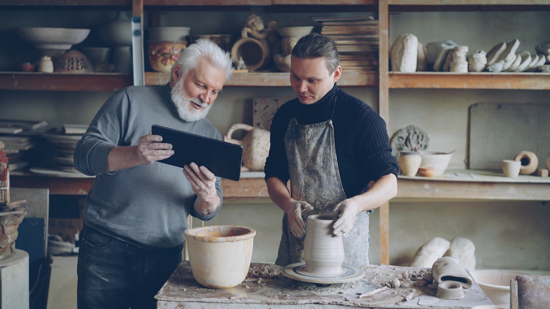Potter guides a younger artist in his craft.