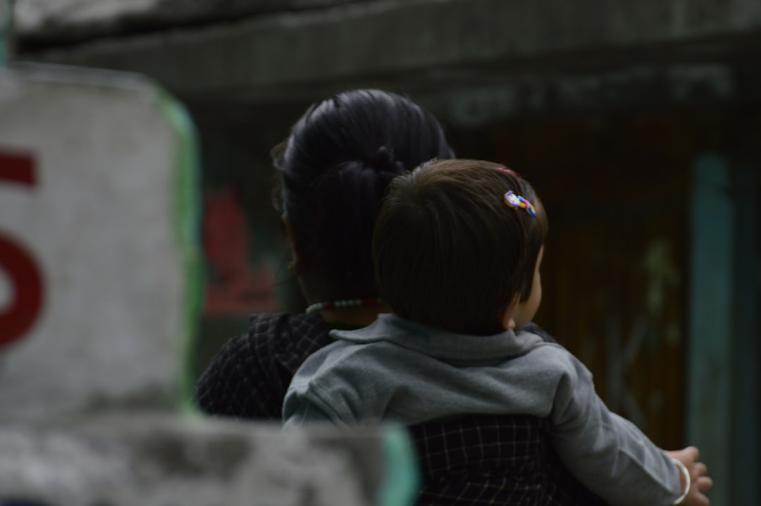 Woman holding a baby, seen from behind.