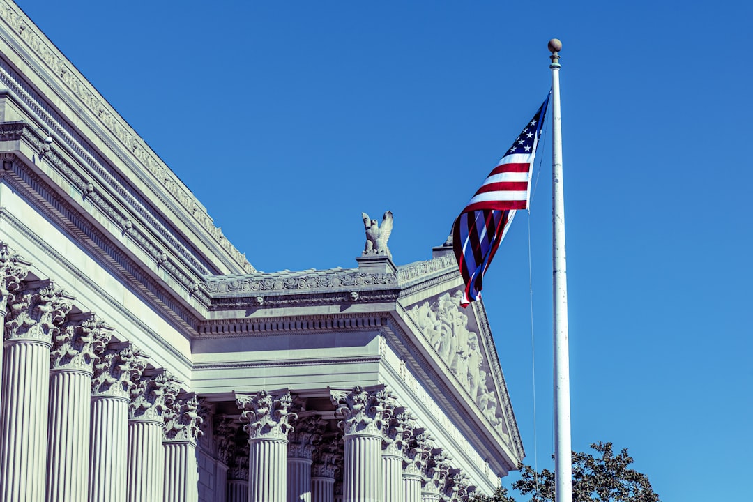 American flag flies in front of classical building.