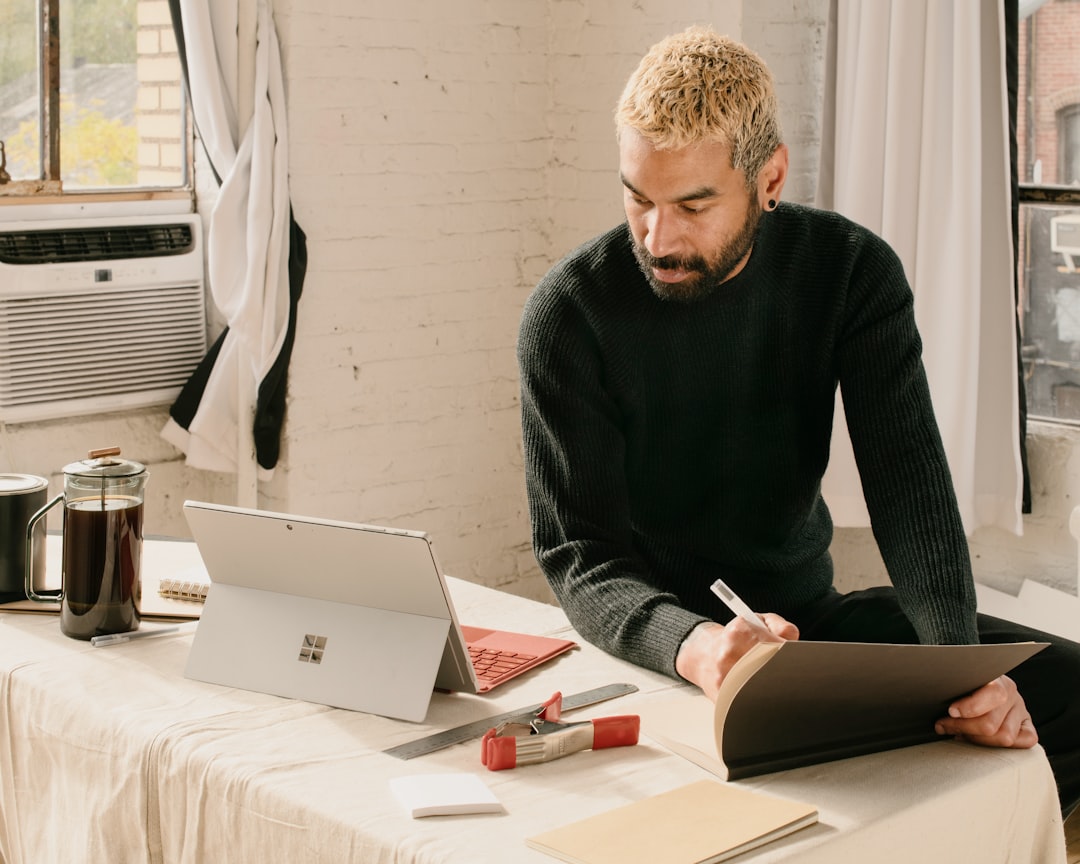 a man sitting at a table with a laptop and notebook