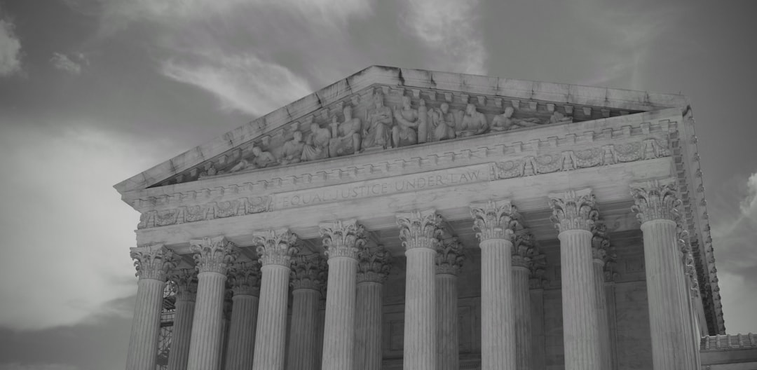 Grand neoclassical building with columns against cloudy sky.